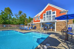 Miamisburg apartment for rent - A red brick house with a blue pool and a blue umbrella.