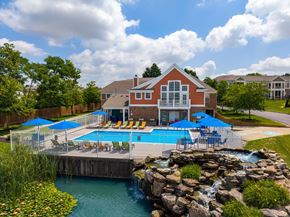 Miamisburg apartment for rent - A red building with a pool and waterfall in front.