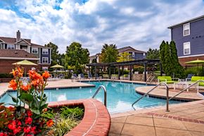 Carmel apartment for rent - A pool surrounded by a brick patio and a flower bed.