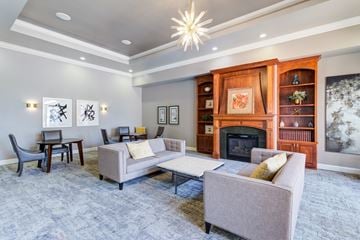 Woodbury apartment for rent - A living room with a grey couch, a chair, a table, a fireplace, and a painting on the wall.