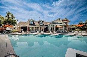 Cincinnati apartment for rent - A large swimming pool in front of a building with a patio and lounge chairs.