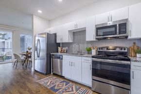 Austin apartment for rent - A modern kitchen with stainless steel appliances and white cabinets.