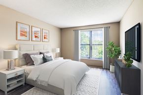 St. Louis Park apartment for rent - A bedroom with a large bed, a nightstand with a lamp, and a flat-screen TV mounted on the wall.