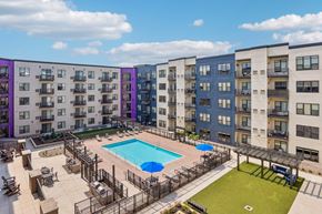 Burnsville apartment for rent - A swimming pool is surrounded by a fence and chairs in a courtyard surrounded by apartment buildings.