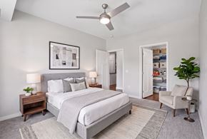 Burnsville apartment for rent - A bedroom with a large bed, a ceiling fan, and a chair.