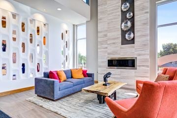 Denver apartment for rent - A living room with a grey couch and a red chair.