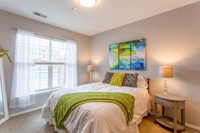 Plymouth apartment for rent - A bedroom with a bed, a nightstand, and a window with curtains.