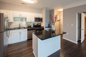 Plymouth apartment for rent - A kitchen with white cabinets and a black island.