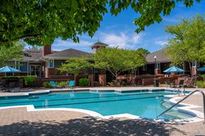 Cary apartment for rent - A swimming pool surrounded by a brick patio and a house with a red roof.
