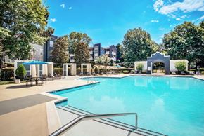 Huntersville apartment for rent - A large swimming pool surrounded by trees and buildings.