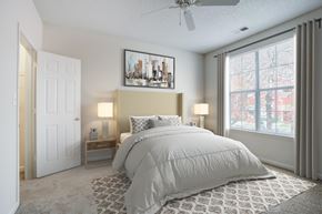 Huntersville apartment for rent - A bedroom with a large bed and a cityscape picture on the wall.