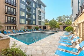 Durham apartment for rent - A swimming pool surrounded by blue lounge chairs and buildings.