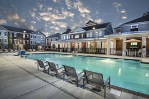 Prospect apartment for rent - A pool surrounded by chairs and buildings at dusk.