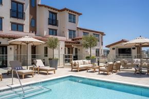 Santa Rosa apartment for rent - A pool area with chairs and umbrellas in front of a building.