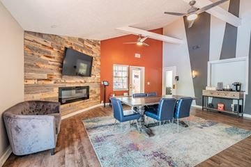 Cincinnati apartment for rent - A living room with a grey sofa, a wooden wall, a TV, a fireplace, and a dining table with chairs.