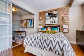 Denver apartment for rent - A bedroom with a large bed and a painting of a cow on the wall.