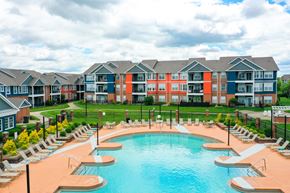 Louisville apartment for rent - A large swimming pool surrounded by lounge chairs in front of apartment buildings.