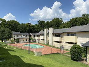 Nacogdoches apartment for rent - A pool surrounded by a fence in a grassy area.