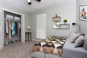 Nacogdoches apartment for rent - A bedroom with a bed, a clothing rack, and a ceiling fan.