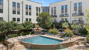 San Antonio apartment for rent - A swimming pool surrounded by chairs and trees in front of apartment buildings.
