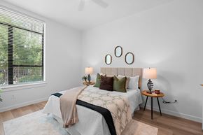 San Antonio apartment for rent - A bedroom with a bed, a small table with a lamp, and a window with blinds.