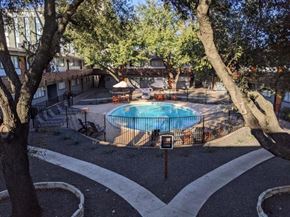 Austin apartment for rent - A pool surrounded by trees and a white fence.