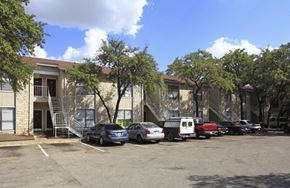 Austin apartment for rent - A parking lot with cars and a building in the background.