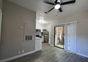 Austin apartment for rent - A room with a ceiling fan and a kitchen area in the background.