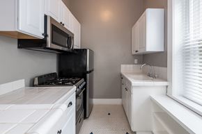 San Diego apartment for rent - A kitchen with white cabinets and black appliances.