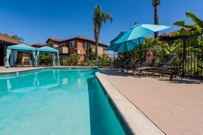 Escondido apartment for rent - A swimming pool with a blue umbrella and a house in the background.