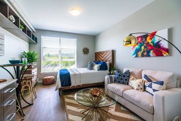 Portland apartment for rent - A living room with a white couch and a bed in the background.