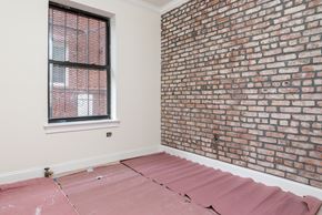 Brooklyn apartment for rent - A room with a brick wall and a window with blinds.