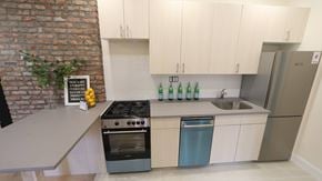 Brooklyn apartment for rent - A kitchen with a brick wall and a stove top oven.