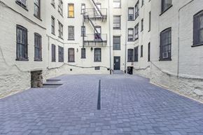 Brooklyn apartment for rent - A long, narrow courtyard between two buildings with a fire escape on the side.