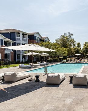 Cordova apartment for rent - A pool surrounded by white cushioned chairs and umbrellas.