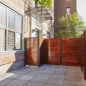 Brooklyn apartment for rent - A brown fence is in front of a building.