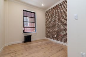 Brooklyn apartment for rent - A room with a brick wall and a window with blinds.