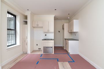 Brooklyn apartment for rent - A kitchen with white cabinets and a black counter top.