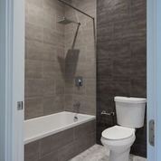 Brooklyn apartment for rent - A white toilet sits next to a bathtub in a bathroom.