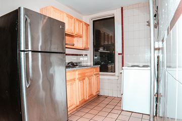 Brooklyn apartment for rent - A kitchen with a black refrigerator and wooden cabinets.
