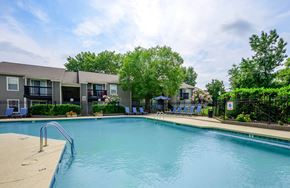 Hendersonville apartment for rent - A swimming pool in front of a building with a blue sky and clouds in the background.