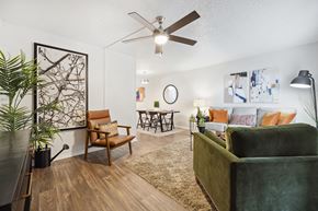 San Antonio apartment for rent - A living room with a green couch, a brown chair, and a wooden floor.