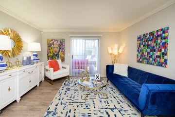 Hendersonville apartment for rent - A blue couch sits in a living room with a white chair and a painting on the wall.