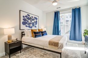 Decatur apartment for rent - A bedroom with a bed, nightstand, and a large blue artwork on the wall.