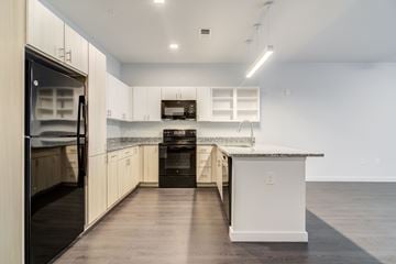 Decatur apartment for rent - A modern kitchen with a black refrigerator and white cabinets.