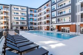 Decatur apartment for rent - A large swimming pool with sun loungers in front of apartment buildings.