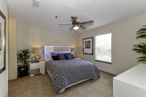 Dawsonville apartment for rent - A bedroom with a patterned bedspread and a ceiling fan.