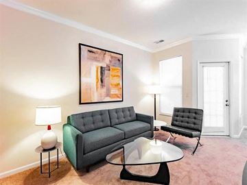 Granger apartment for rent - A living room with a grey couch, a black chair, a glass table and a painting on the wall.