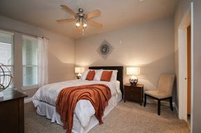 Kingwood apartment for rent - A bedroom with a bed, chair, and ceiling fan.