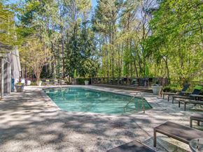 Douglasville apartment for rent - A pool surrounded by trees and a patio with chairs.